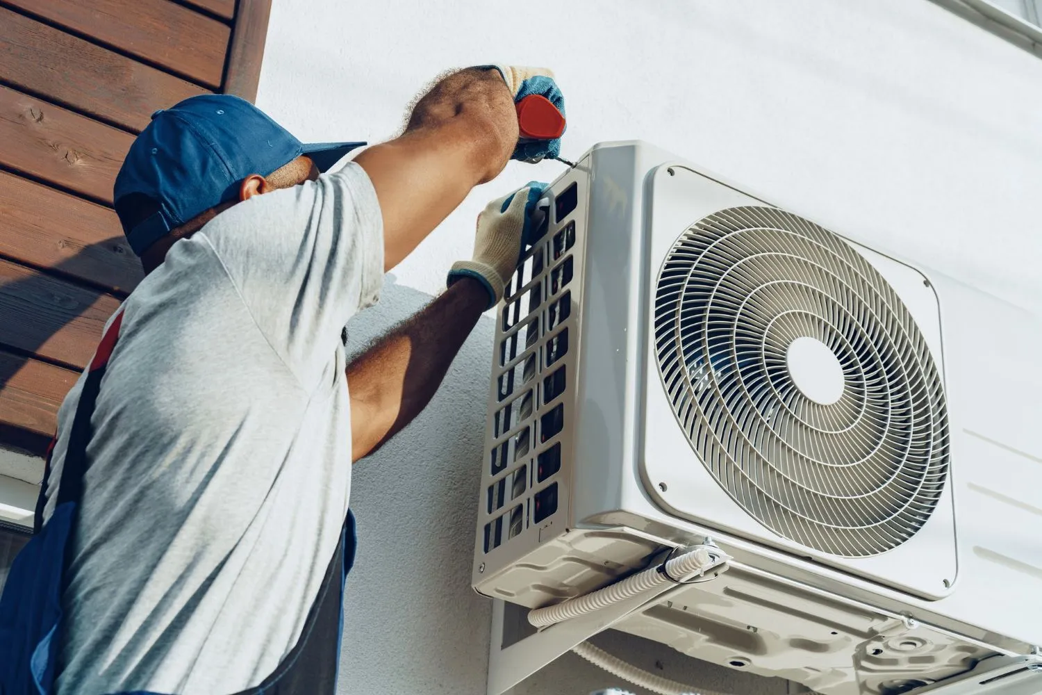 A technician from Reid Heating & Air is installing an air conditioner on the side of a building in Mount Pleasant, SC